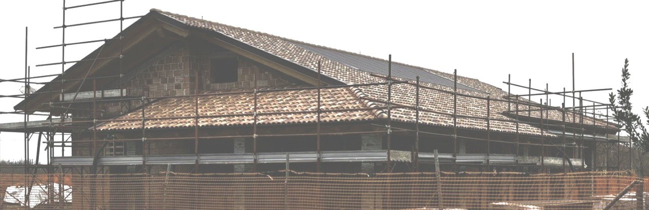 Cantiere di ristrutturazione di un edificio con tetto in laterizio e ponteggi